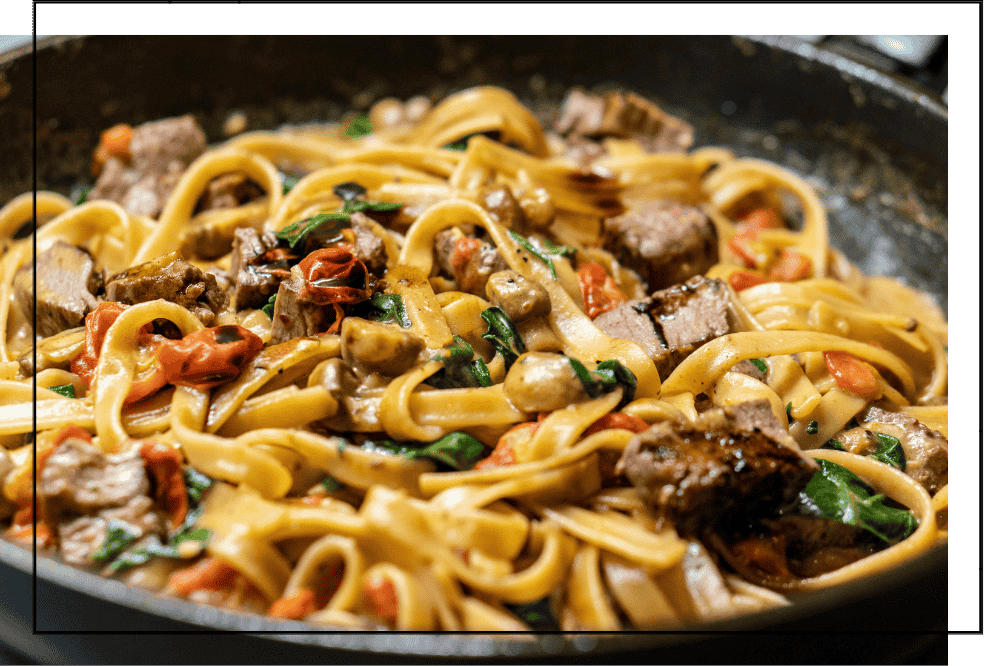 Fettuccine with seared beef, tomatoes, and spinach in a skillet, noodle catering in DFW